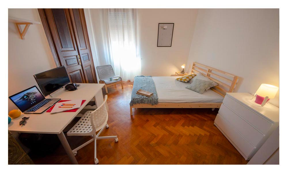 vista generale della stanza, compresa di letto matrimoniale, cassettiera e scrivania