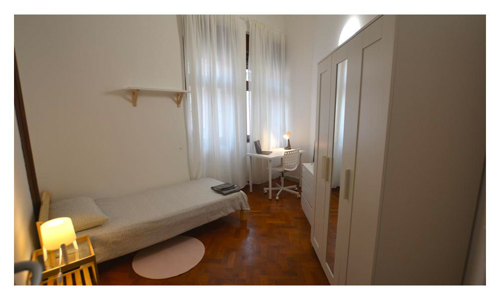 vista generale della stanza singola composta da letto singolo, armadio con specchio, zona studio e finestra