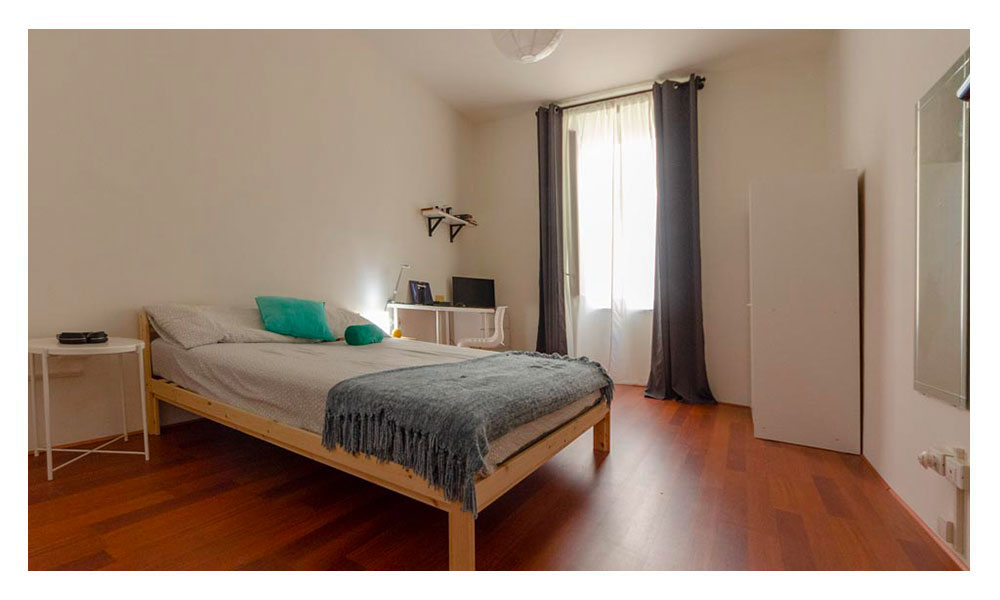 vista della suite con letto matrimoniale, comodino, armadio, scrivania con sedia e finestra