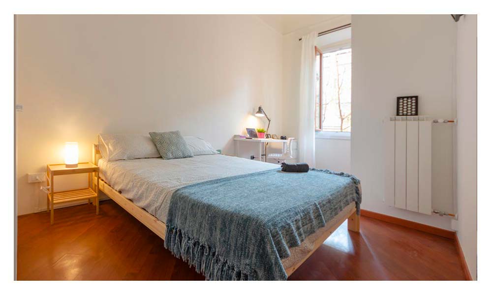 vista della stanza con letto matrimoniale arredato con un copriletto blu