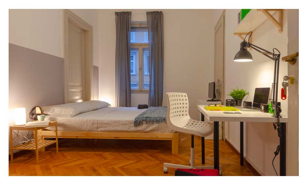 panoramica della stanza, con letto matrimoniale, tavolo e scrivania, lampada e comodini