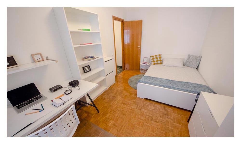 vista generale della stanza arredata con letto matrimoniale, libreria e zona studio lavoro